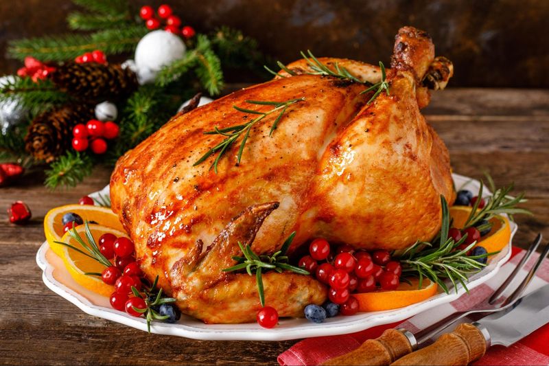 Roasted turkey with cranberry sauce and cranberries on a wooden table.