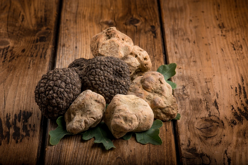 Mix of black and white truffles on wood slats.