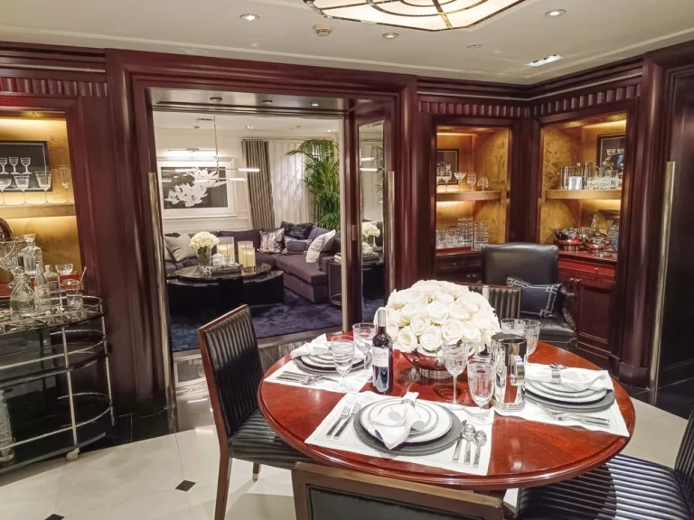 Luxury yacht interior with tableware, crockery, glasses and central flower arrangement.