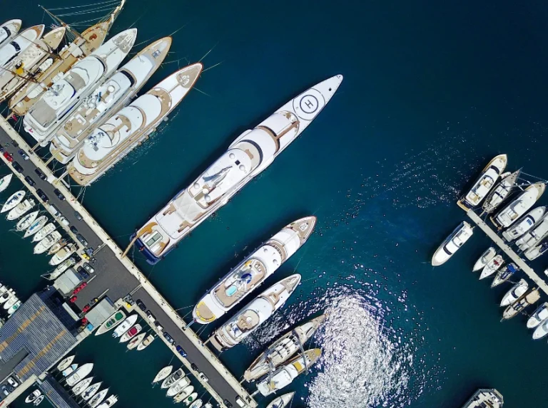 Arial view of big yachts and small yachts docked in a marina.