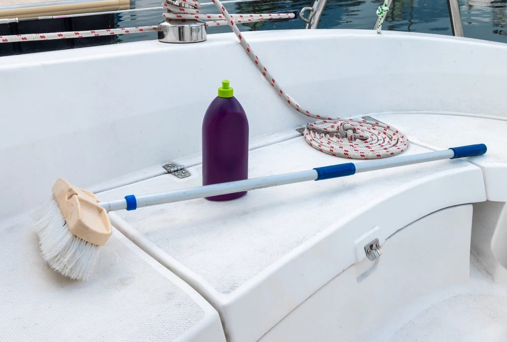 A brush and a cleaning solution in a bottle on a seat in the yacht exterior.